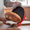 "Le Creuset Enameled Cast Iron Bread Oven in Flame color, featuring a vibrant orange-red finish with a domed lid, perfect for baking artisan-quality bread at home."