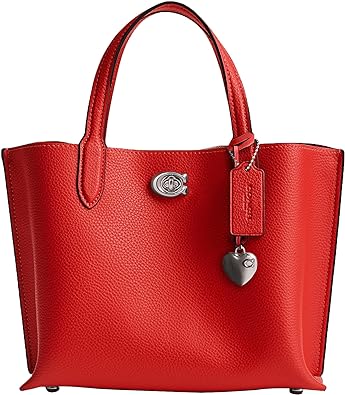 “Elegance meets playfulness in the Coach Polished Pebble Leather Willow Tote 24. Crafted from luxurious pebble-grain leather, this medium-sized tote features a structured silhouette, sturdy handles, and a delightful heart-shaped charm. Perfect for adding a dash of romance to your everyday style!”